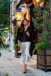 a lady wears a black tweed jacket with satin midi skirt